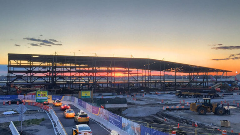 View of LaGuardia's Terminal B steel framework against a glowing sky as the sun rises